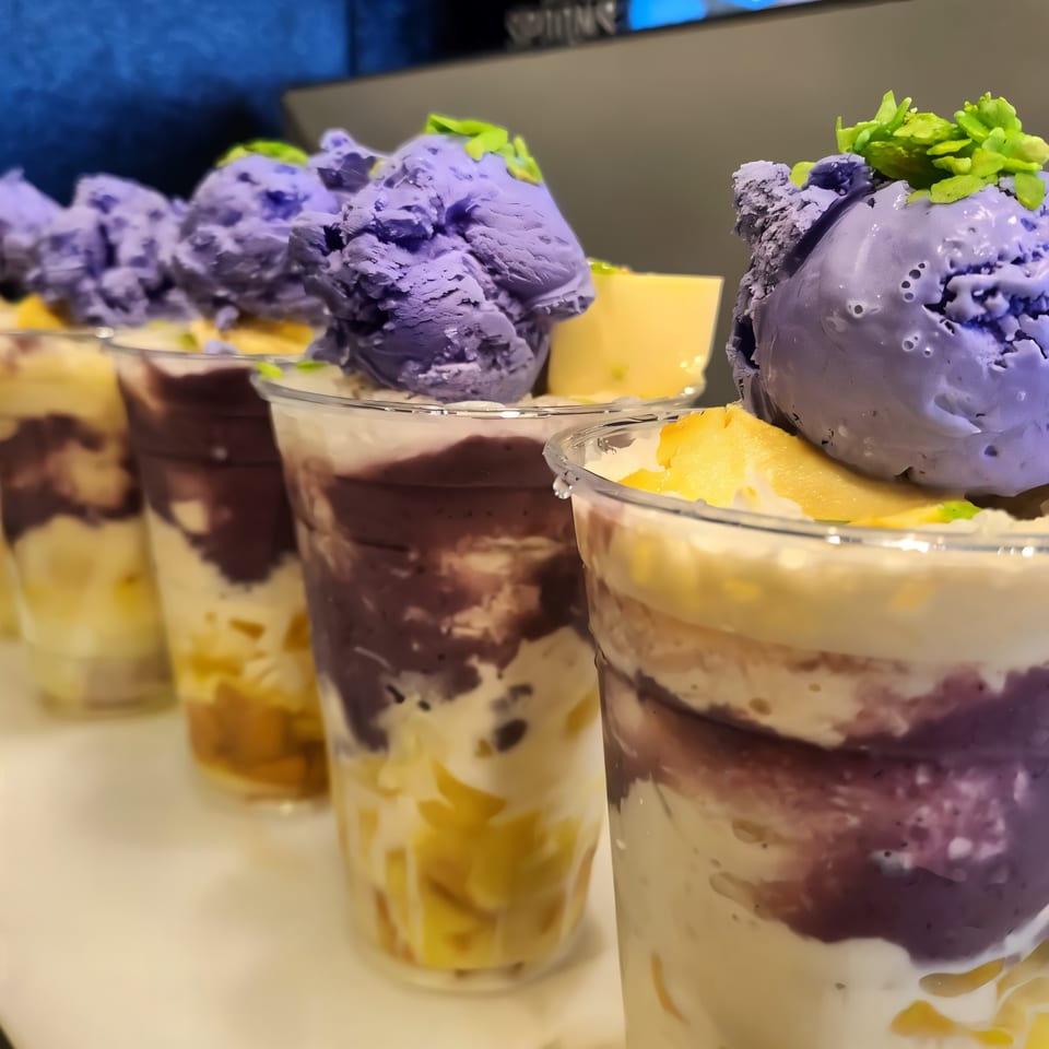 Row of Filipino halo-halo desserts with purple ube ice cream, leche flan, and green toppings.