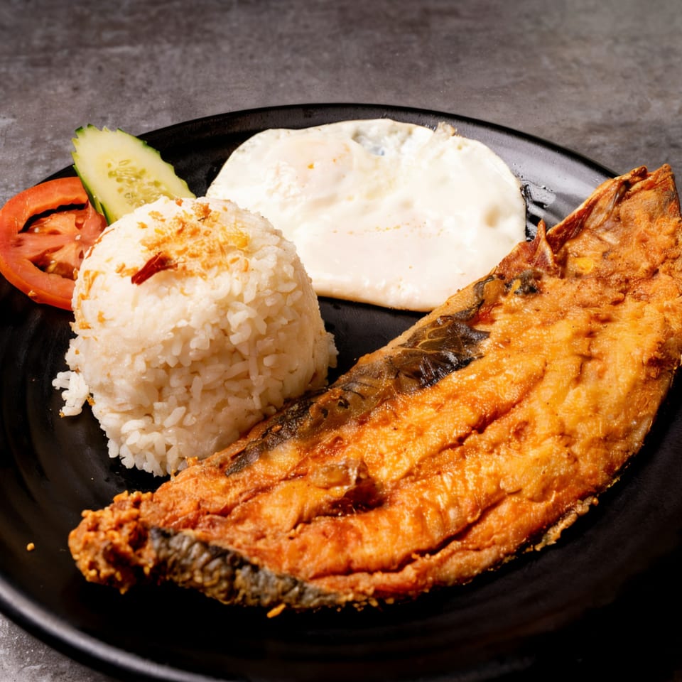 A Filipino silog meal with fried bangus, garlic rice, fried egg, tomato, and cucumber.